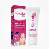 Conceive Plus Fertility Lubricant (2.5 fl. oz) tube and box displayed side by side, featuring a white squeeze tube with pink branding and a matching retail box showing product benefits like pH balance and sperm quality support, with a baby image at bottom for visual emphasis on fertility use.